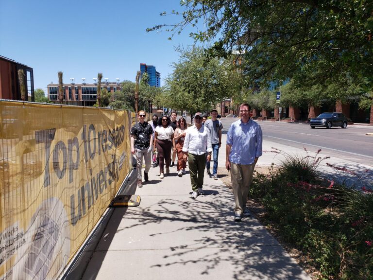 People walking toward photographer on a sidewalk next to an ASU construction site.