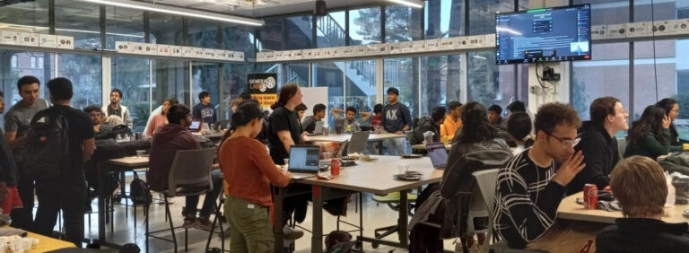 Room full of students at desks at a student Hackathon event.