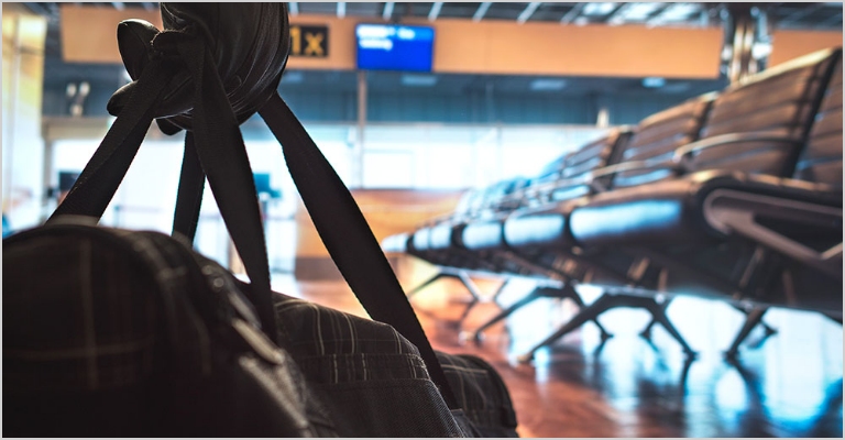 Hand of a person holding a carry-on bag in an terminal.
